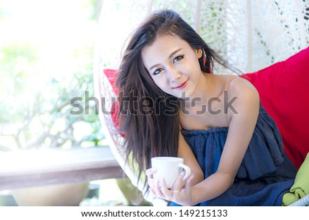 young sexy Asian female long brown hair in navy dress hold coffee cup