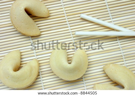Background of Chinese fortune cookies on bamboo stick mat, with chopsticks.