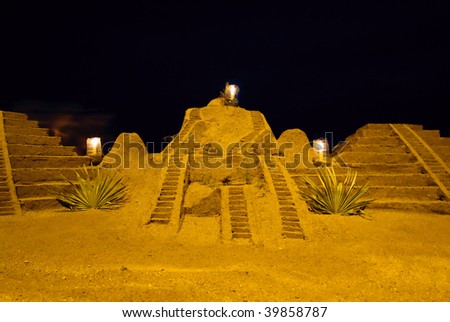 Pyramids made from sand and illuminated by candles at the beach against dark sky in the night.