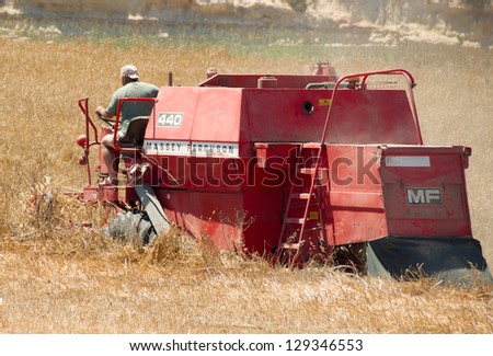 MALTA, GOZO - JUNE 7: A farmer at Gozo Island harvests a field being almost too small to turn-over the harvester.  June 7th, 2012 at Gozo, Malta.