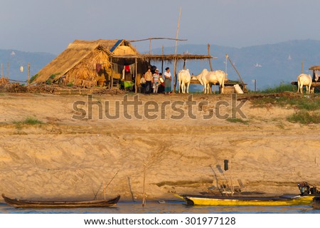 Mandalay, Myanmar - November 19:  Farmers at a bank of Irrawaddy River prepare for their daily work in the early morning sun. November 19, 2015 in Mandalay, Myanmar