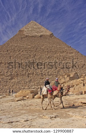 CAIRO, EGYPT - DECEMBER14: Unidentified camel men lead their camels along Pyramid of Khafre on December 14, 2010 in Cairo, Egypt. Pyramid of Khafre is the second largest of ancient Pyramids of Giza.