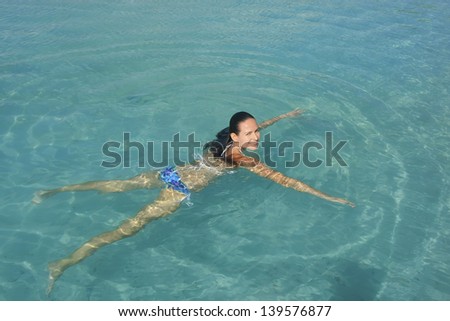Young woman in bikini swimming in clear water