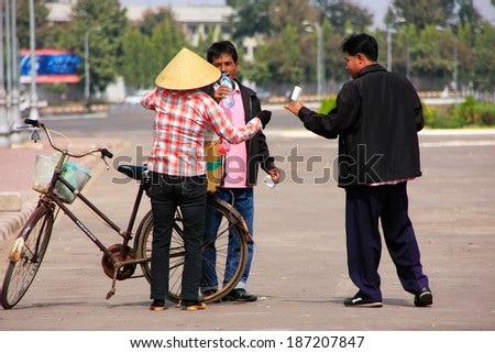 VIENTIANE, LAOS - NOVEMBER 29: Unidentified men buy ice cream from street seller on November 29, 2011 in Vientiane, Laos. Vientiane is the capital and largest city of Laos.