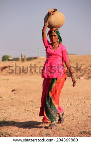 KHICHAN, INDIA - FEBRUARY 12: An unidentified woman carries jar with water on her head on February 12, 2011 in Khichan, India.