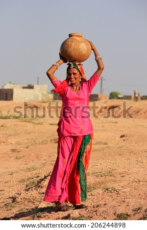 KHICHAN, INDIA - FEBRUARY 12: An unidentified woman carries jar with water on her head on February 12, 2011 in Khichan, India.