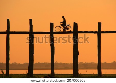 Silhouetted person with a bike on U Bein Bridge at sunset, Amarapura, Mandalay region, Myanmar