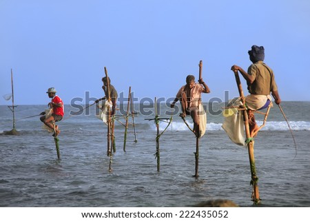 UNAWATUNA, SRI LANKA - JANUARY 1: Unidentified men fish on sticks on January 1, 2011 in Unawatuna, Sri Lanka. Unawatuna is a major tourist attraction and famous for its beautiful beach and corals.