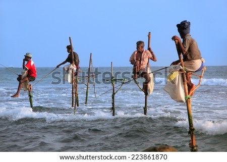 UNAWATUNA, SRI LANKA - JANUARY 1: Unidentified men fish on sticks on January 1, 2011 in Unawatuna, Sri Lanka. Unawatuna is a major tourist attraction and famous for its beautiful beach and corals.