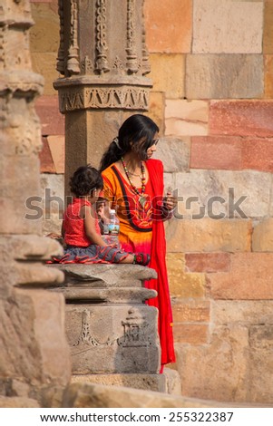 DELHI, INDIA - NOVEMBER 4: Unidentified woman with unidentified child stands in  mosque courtyard at Qutub Minar complex on November 4, 2014 in Delhi, India. Qutub Minar is the tallest minar in India