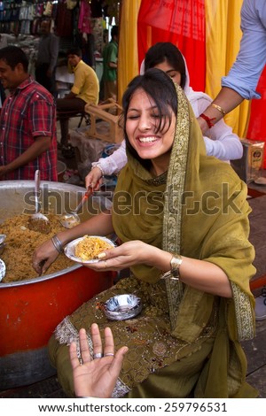 DELHI, INDIA - NOVEMBER 5: Unidentified woman gives away rice during Guru Nanak Gurpurab celebration on November 5, 2014 in Delhi, India. This festival celebrates the birth of the first Sikh Guru.