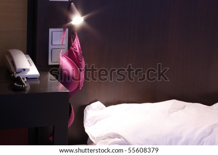 Double bed with purple bra hanging on the bed side lamp.