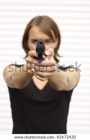 Attractive female pointing a gun.