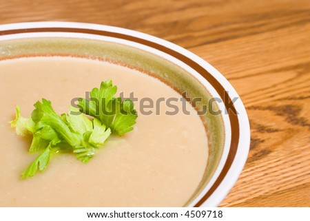 Celery root bisque in a stoneware bowl with celery leaf garnish