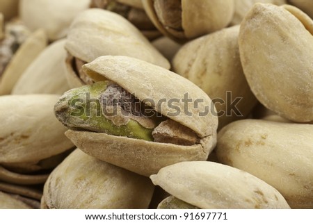 A pile of roasted salted pistachios one close-up showing it\'s seed