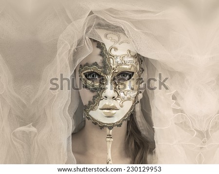 Beautiful young woman in mysterious golden Venetian mask.