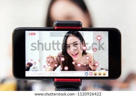Asian woman professional beauty vlogger or blogger live broadcasting cosmetic makeup tutorial viral video clip by smartphone sharing on social media