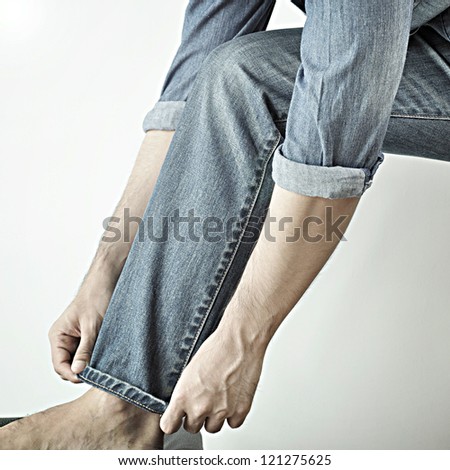 Man wearing jeans folding up pant leg