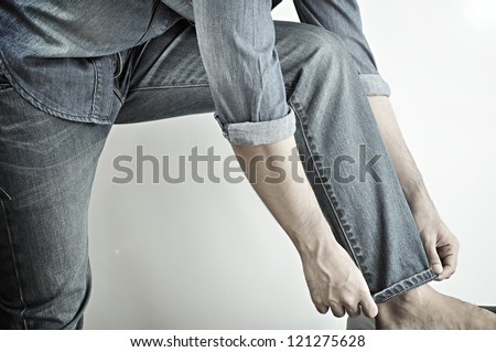 Man wearing jeans folding up pant leg