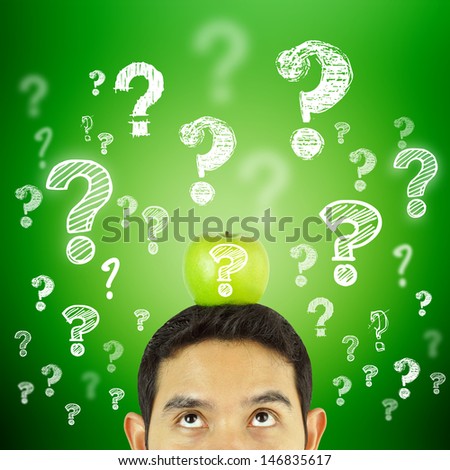 Thoughtful man with green apple and question marks over his head