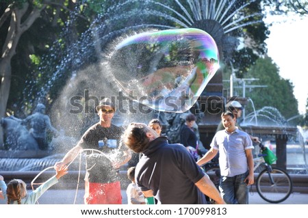 Sydney Australia - April 25, 2013: People Playing Big Bubble In Hyde Park Sydney - The Oldest Public Parkland In Australia Located In The Central Business District Of Sydney