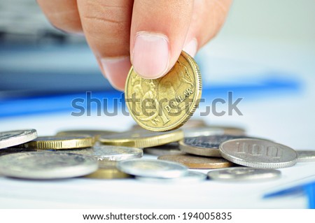 Fingers picking up a coin - one Australian dollar (AUD)