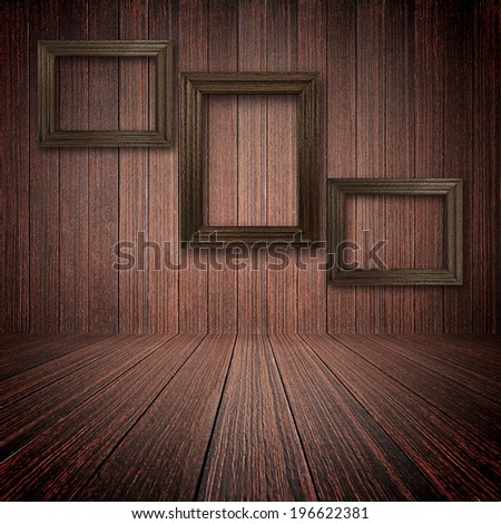 Three wooden picture frames on the wall inside dark wooden room