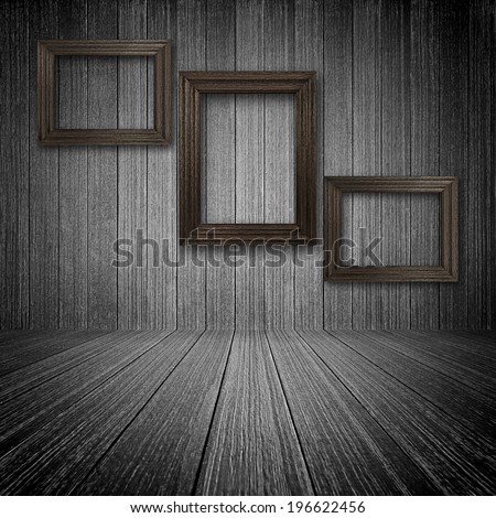 Three wooden picture frames on the wall inside dark wooden room