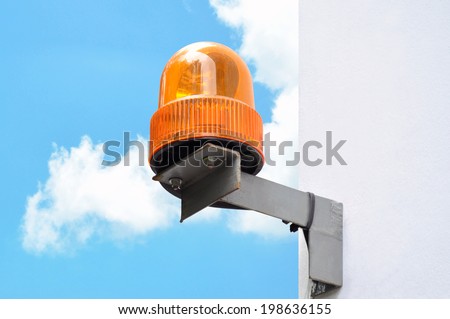Revolving amber light beacon or siren at corner of building