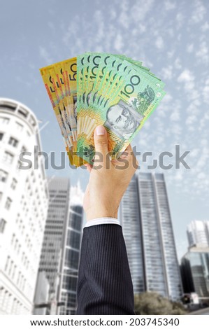 Hand holding money - Australian dollars (AUD) - on building background