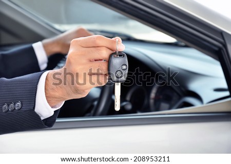 Hand holding a car key - car sale & rental business concept