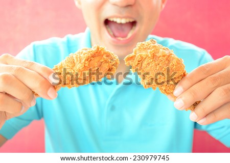 A man with opening mouth about to eat deep fried chicken legs or drumsticks