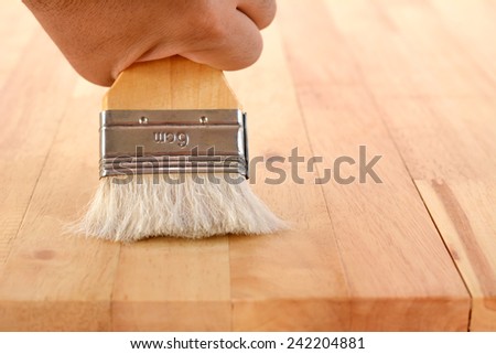 Hand with brush on wood table top
