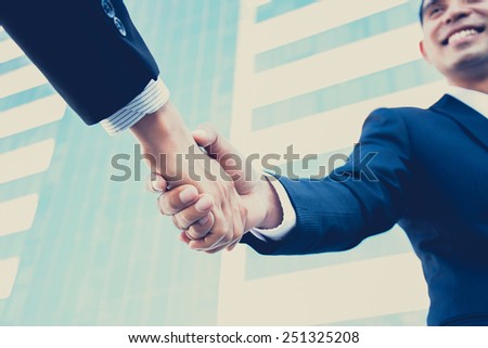 Handshake of businessmen with smiling face, greeting, dealing, partnership, merger & acquisition concepts  - vintage & retro style color effect