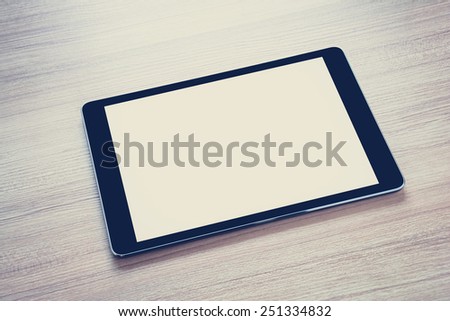 Tablet computer (isolated screen) on wooden table - vintage & retro style color effect