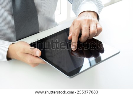 Businessman using tablet pc on the table with one hand touching the screen
