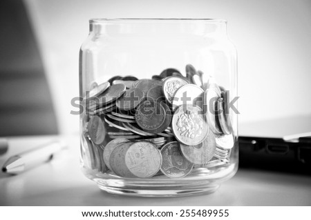 Coins in the glass jar, mixed Asian multi currencies - monochrome effect