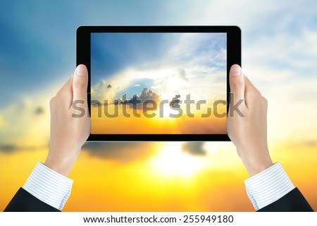 Businessman hands holding tablet pc, taking picture of the sun shining in the sky - bright business concept