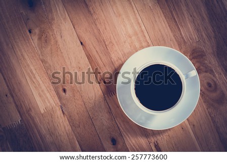 Coffee cup with black coffee on wooden table (top view) - soft focus with vintage color effect
