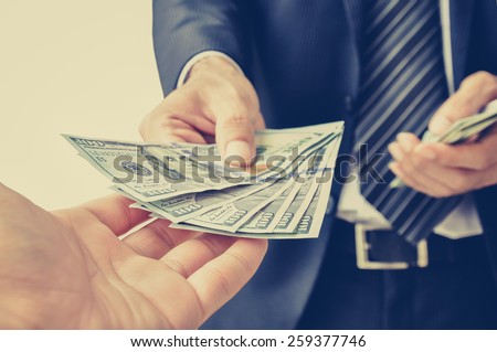 Hand receiving money, US dollar (USD) bills, from businessman hand - vintage style color effect