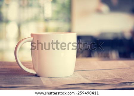 Coffee cup on newspaper in coffee shop - vintage (retro) style color effect