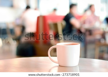 Hot drink on the table with people sitting in cafe as blur background - soft focus