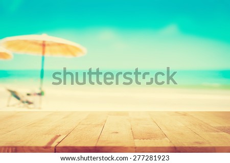 Wood table top on blurred blue sea and white sand beach background, vintage tone - can be used for display or montage your products