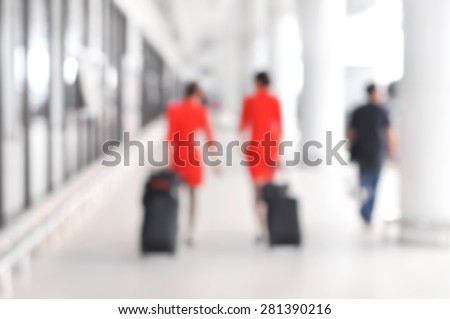 Blurred people and flight attendants walking at the airport hallway