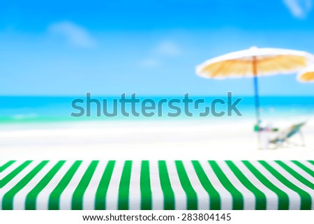 Table top covered with striped tablecloth on blurred beach background, picnic and holiday concepts - can be used for display and montage your products
