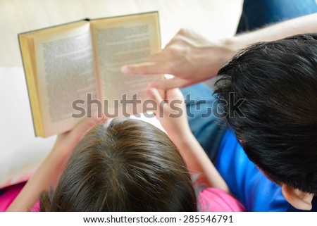 Couple sitting together, reading book - top view