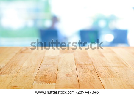 Wood table top on blur  background of a person sitting in bright room - can be used for montage or display your products