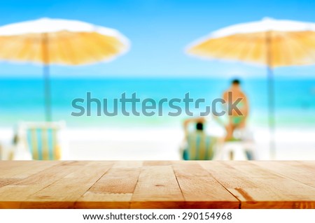 Wood table top on blurred white sand beach background with some people - can be used for montage or display your products