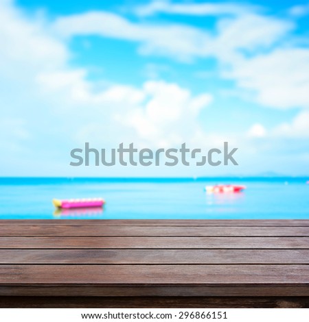 Wood table top on blur summer sky and sea with banana boats as background - can be used for display or montage your products