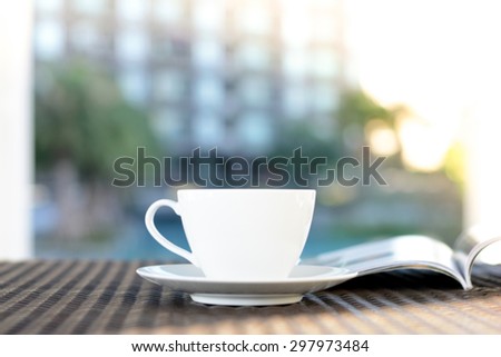 Blurred coffee cup with opened book on outdoor rattan table in the morning - chilling out in resort or hotel concept